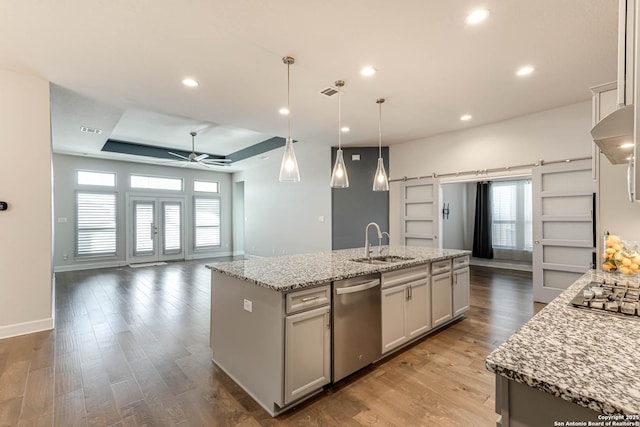 kitchen featuring appliances with stainless steel finishes, a barn door, and an island with sink