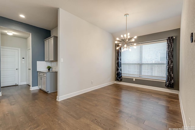 unfurnished dining area featuring dark wood-type flooring and an inviting chandelier