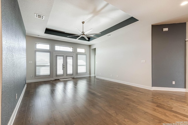 spare room featuring ceiling fan, dark wood-type flooring, and a tray ceiling