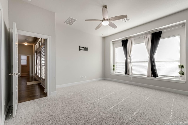 empty room featuring ceiling fan and dark carpet