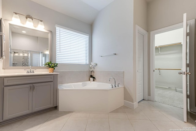 bathroom featuring tile patterned flooring, vanity, a bath, and lofted ceiling