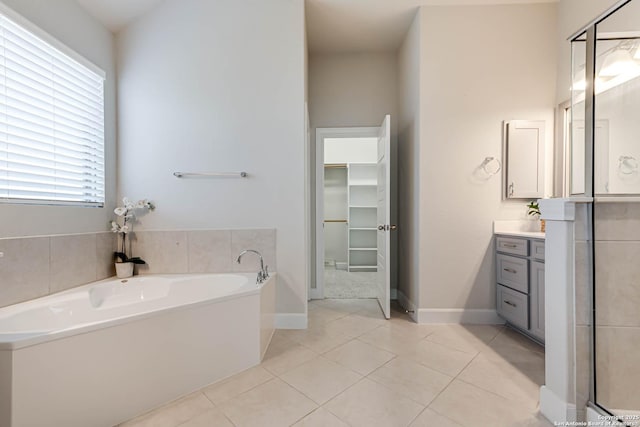 bathroom with a washtub, vanity, tile patterned floors, and plenty of natural light