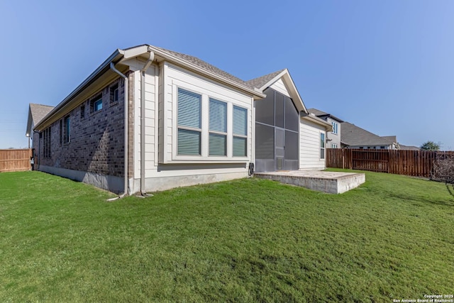 back of property with a sunroom, a patio area, and a yard