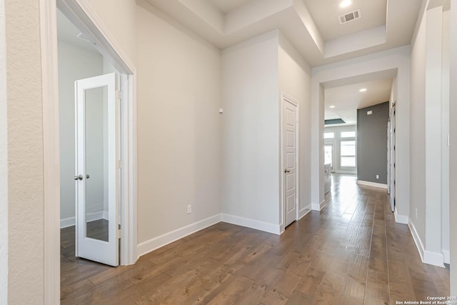 corridor with a raised ceiling and dark hardwood / wood-style floors