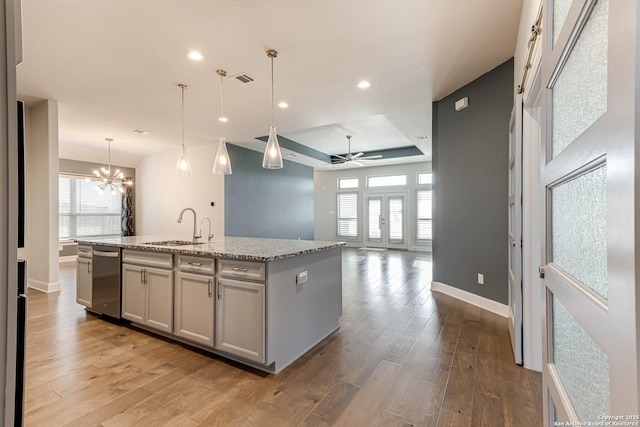 kitchen with a center island with sink, decorative light fixtures, ceiling fan with notable chandelier, and sink