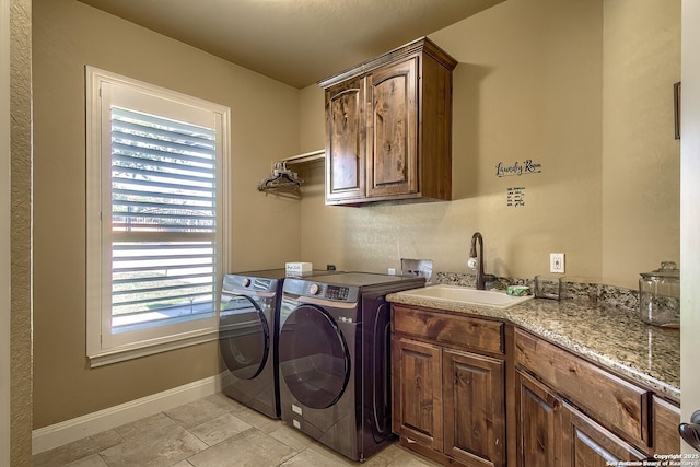 clothes washing area with cabinets, plenty of natural light, washer and clothes dryer, and sink