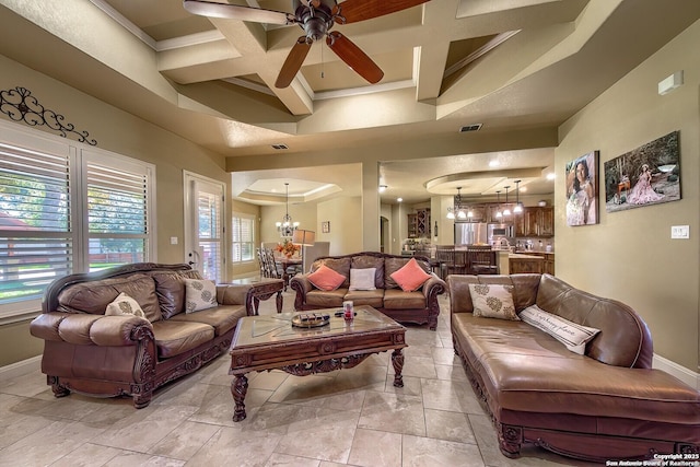 living room with beam ceiling, a high ceiling, coffered ceiling, ceiling fan with notable chandelier, and ornamental molding