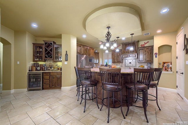 kitchen with decorative backsplash, a kitchen bar, stainless steel appliances, a center island, and wine cooler