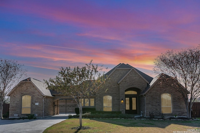 french country inspired facade with a yard and a garage