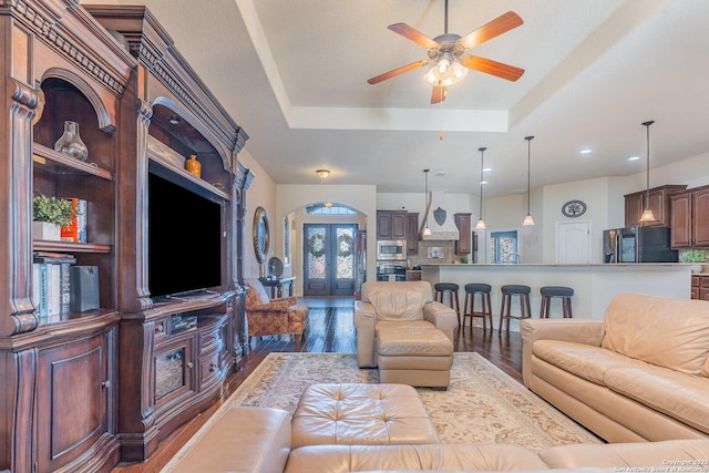 living room featuring dark hardwood / wood-style floors, ceiling fan, and a raised ceiling