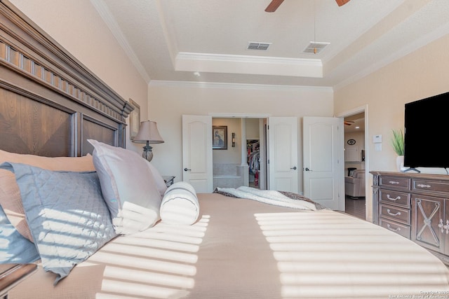 bedroom with a tray ceiling, ceiling fan, crown molding, and ensuite bathroom