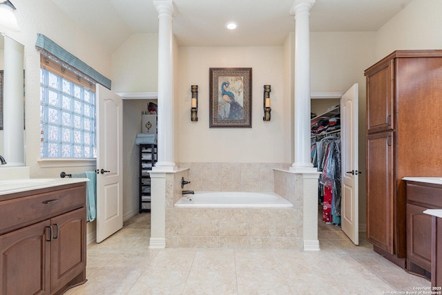 bathroom featuring tile patterned flooring, vanity, lofted ceiling, and tiled bath