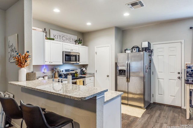 kitchen featuring a kitchen breakfast bar, kitchen peninsula, white cabinetry, and stainless steel appliances