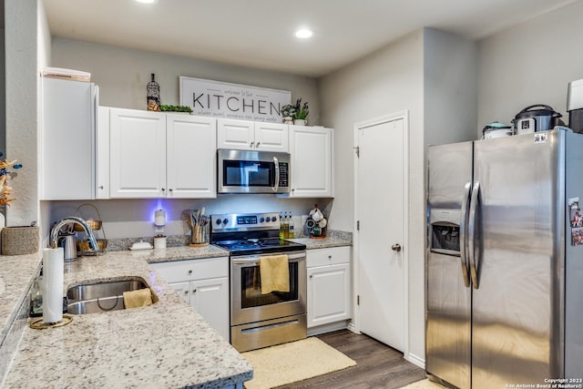 kitchen featuring light stone countertops, sink, dark wood-type flooring, stainless steel appliances, and white cabinets