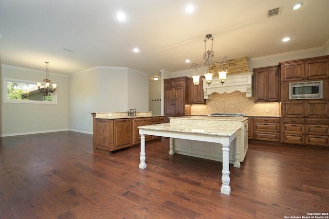 604 Hannahs Run, New Braunfels, TX 78130 - kitchen featuring stainless steel microwave, an island with sink, a chandelier, tasteful backsplash, and crown molding