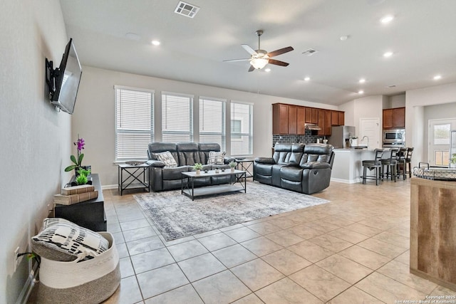 living room featuring ceiling fan, light tile patterned flooring, a healthy amount of sunlight, and lofted ceiling