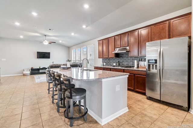 kitchen featuring sink, vaulted ceiling, an island with sink, tasteful backsplash, and stainless steel appliances