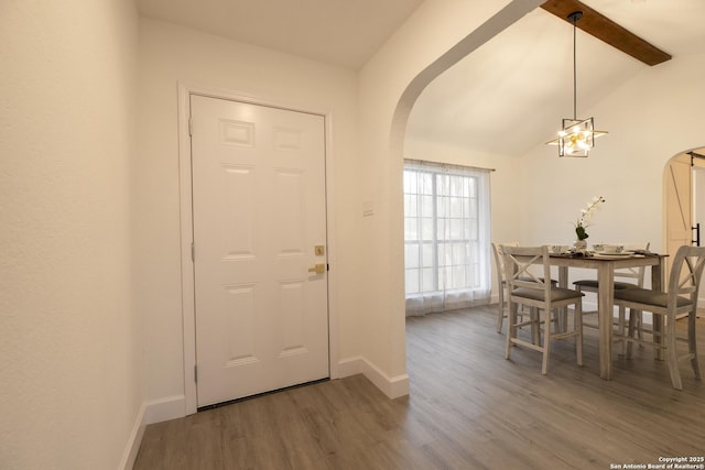 entrance foyer with a chandelier, hardwood / wood-style floors, and lofted ceiling with beams