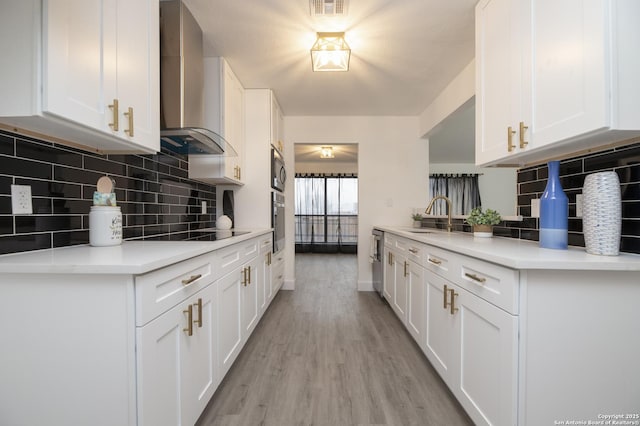 kitchen featuring white cabinets, wall chimney range hood, backsplash, and appliances with stainless steel finishes