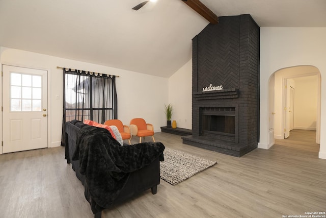 living room featuring a fireplace, lofted ceiling with beams, light hardwood / wood-style floors, and ceiling fan