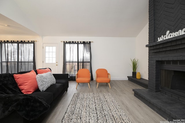 living room with a fireplace, light hardwood / wood-style floors, and vaulted ceiling