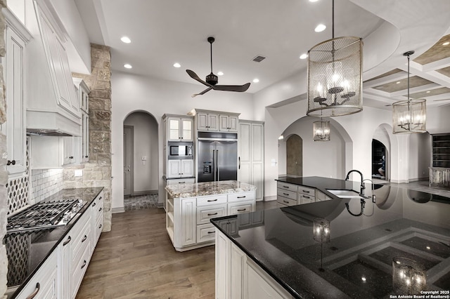 kitchen featuring pendant lighting, a spacious island, sink, built in appliances, and tasteful backsplash