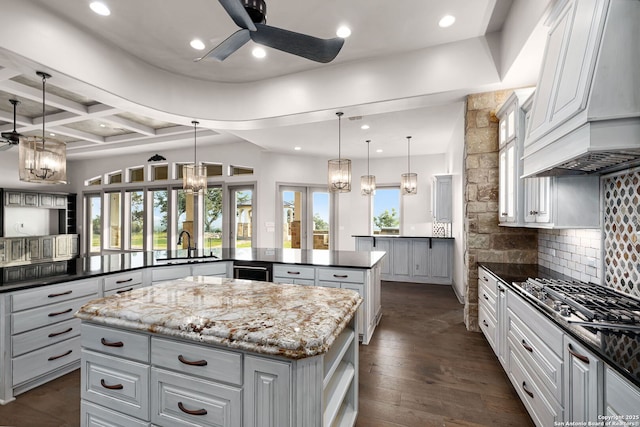 kitchen featuring premium range hood, kitchen peninsula, a kitchen island, and hanging light fixtures