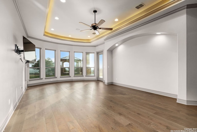 empty room featuring hardwood / wood-style floors, a tray ceiling, ceiling fan, and ornamental molding