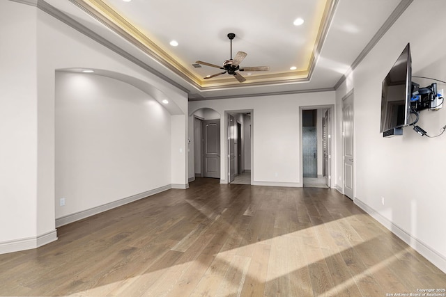 unfurnished room featuring ceiling fan, a raised ceiling, ornamental molding, and wood-type flooring