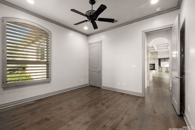 interior space with a fireplace, dark hardwood / wood-style flooring, ceiling fan, and ornamental molding