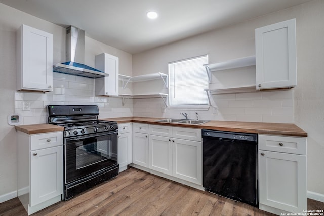 kitchen featuring wall chimney range hood, butcher block countertops, white cabinetry, and black appliances