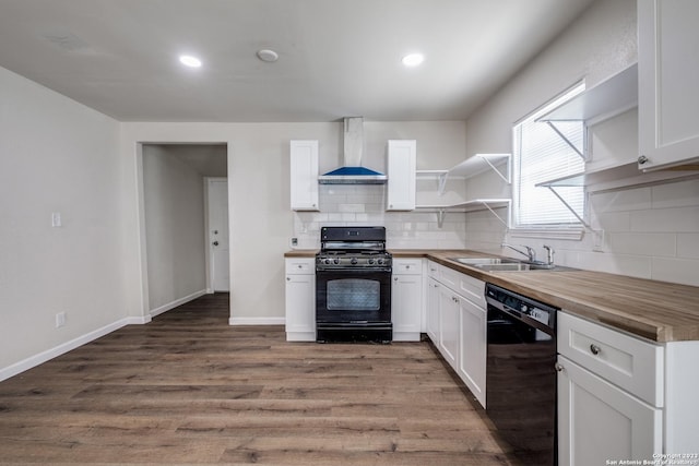 kitchen with wooden counters, black appliances, sink, wall chimney exhaust hood, and white cabinetry