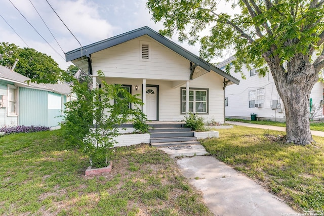 bungalow-style house with a front yard, cooling unit, and covered porch