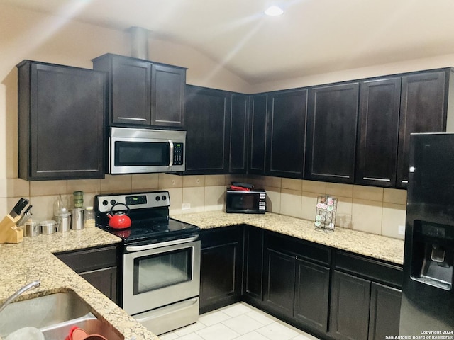 kitchen featuring decorative backsplash, light stone countertops, sink, black appliances, and light tile patterned flooring