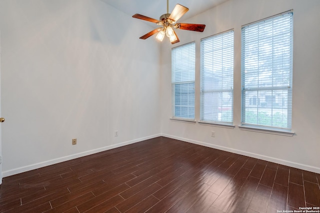 empty room featuring a wealth of natural light, ceiling fan, and dark wood-type flooring