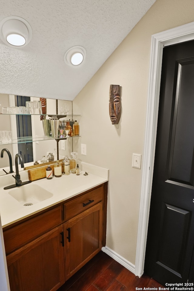 bathroom featuring vanity, lofted ceiling, and a textured ceiling