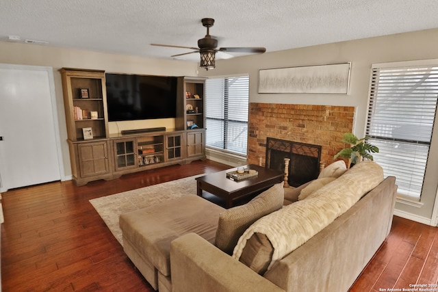 living room featuring ceiling fan, a textured ceiling, and a brick fireplace