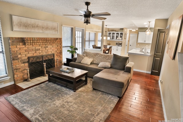 living room featuring a fireplace, ceiling fan, hardwood / wood-style floors, and a textured ceiling