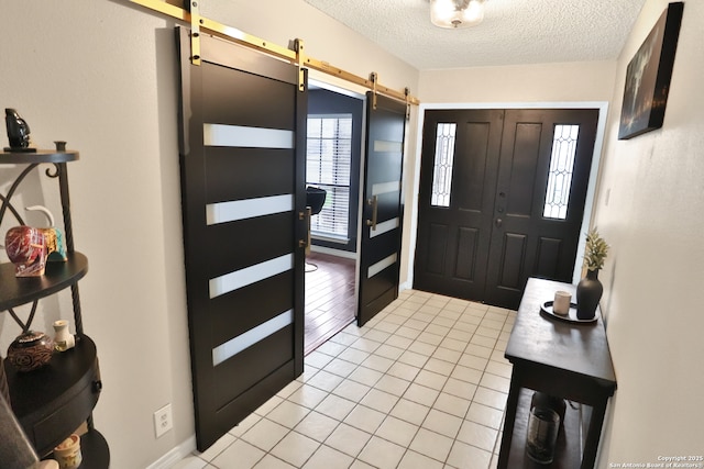 tiled entryway featuring a barn door and a textured ceiling