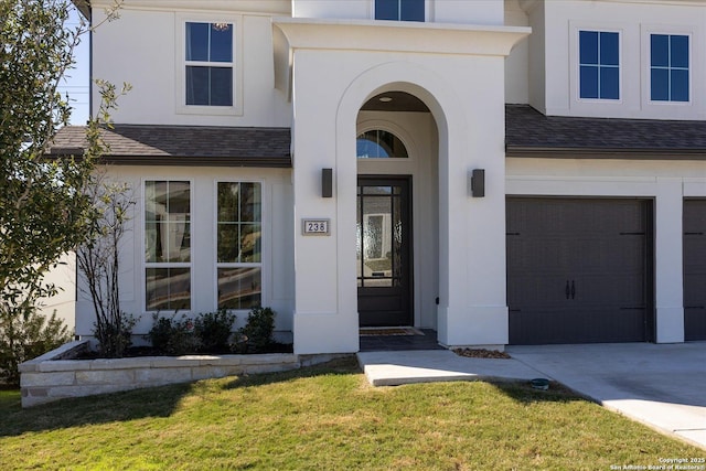 view of exterior entry with a garage and a yard