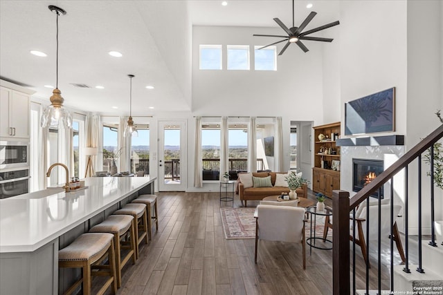 living room with ceiling fan, a fireplace, a high ceiling, and sink