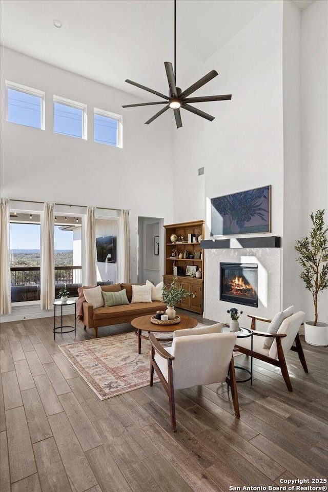 living room with ceiling fan, a towering ceiling, and wood-type flooring