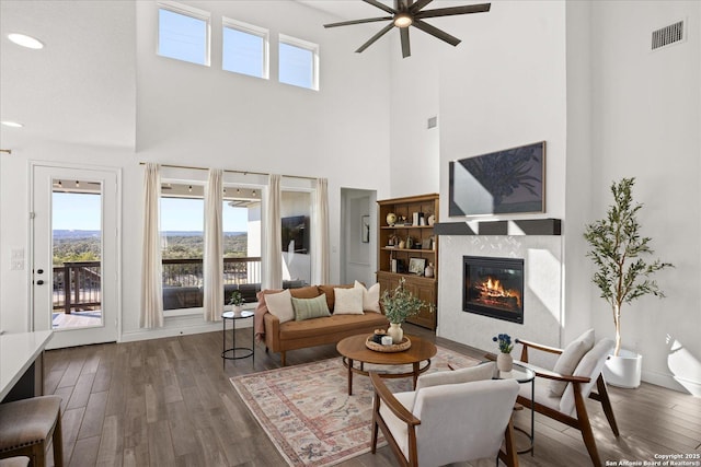 living room with ceiling fan, dark wood-type flooring, and a high ceiling