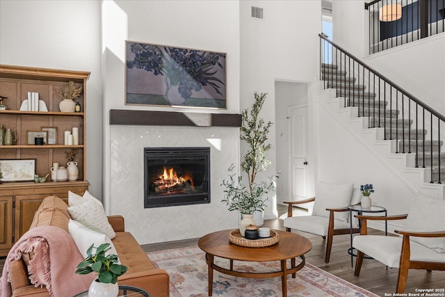 living room with a fireplace, a high ceiling, and hardwood / wood-style flooring