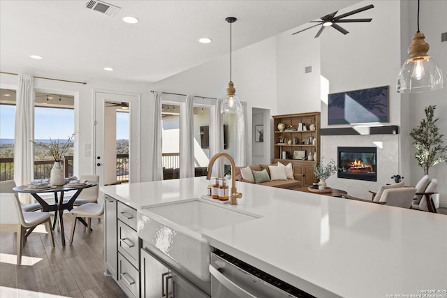 kitchen featuring sink, vaulted ceiling, stainless steel dishwasher, decorative light fixtures, and dark hardwood / wood-style flooring