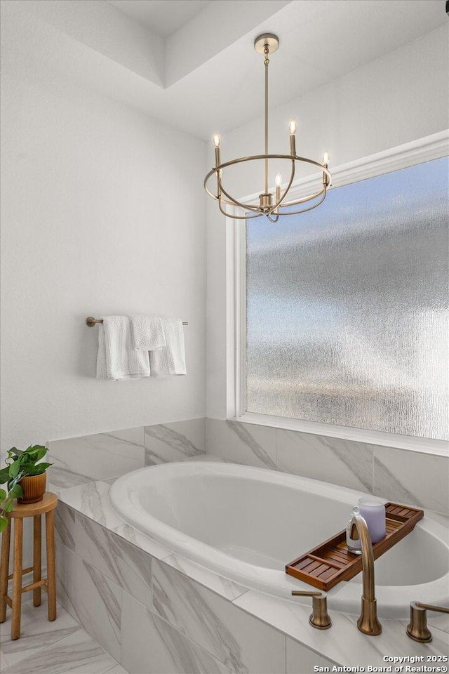 bathroom featuring a relaxing tiled tub and a notable chandelier