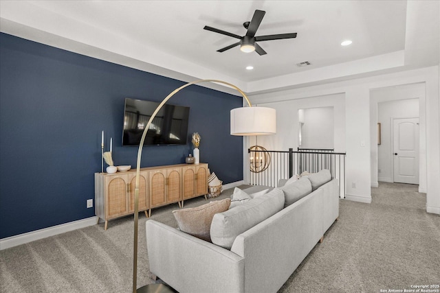 carpeted living room featuring ceiling fan and a raised ceiling