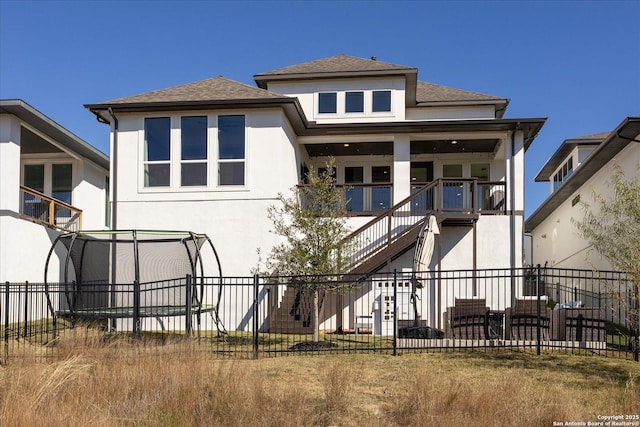 back of property with a yard and a trampoline