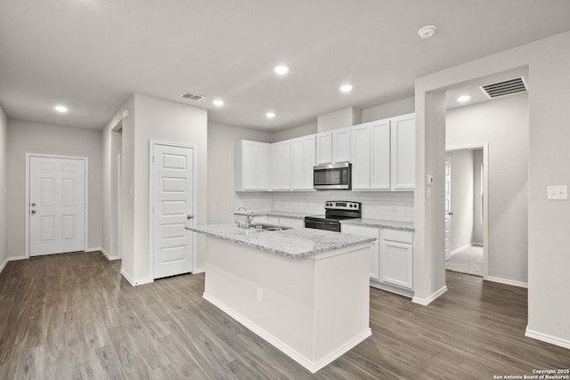 kitchen featuring decorative backsplash, appliances with stainless steel finishes, light stone counters, white cabinets, and light hardwood / wood-style floors