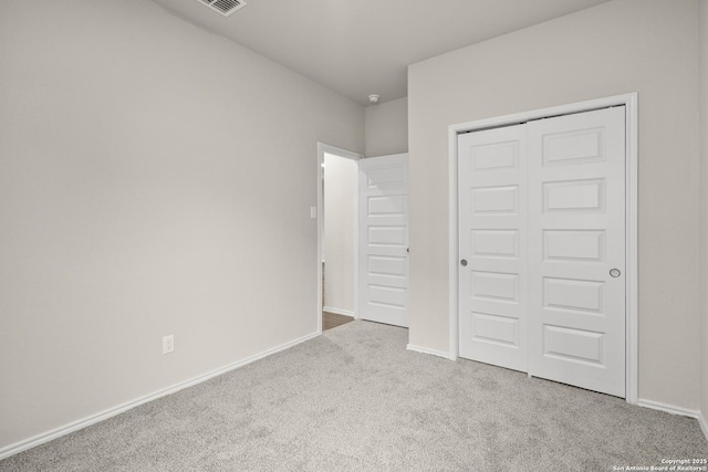 unfurnished bedroom featuring light carpet and a closet